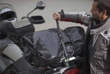 Black bungee straps securing a motorcycle seat bag with metal hardware at corners.